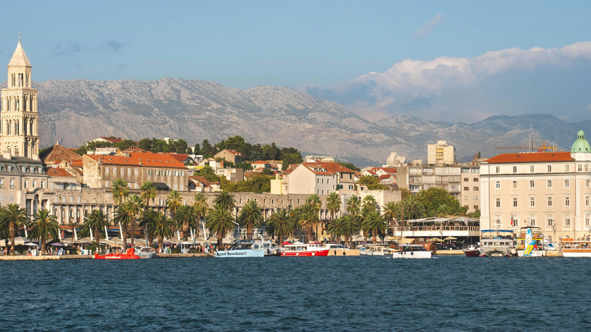 Stad aan de zee met bergen in de achtergrond.
