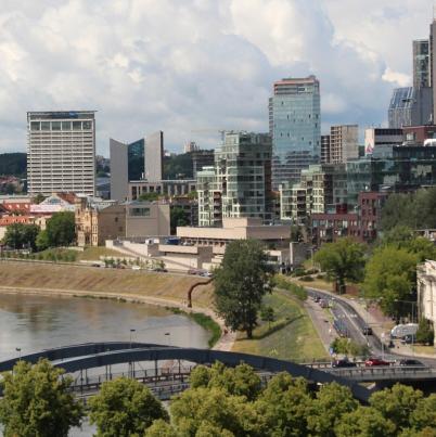 Stad aan een rivier met veel groen en hoogbouw.