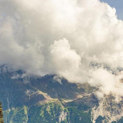 Zwitserse vlag met op de achtergrond bergen en wolken.