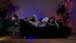 Foto van Klokhuispresentator Pascal die op de bank naar zijn smartphone kijkt.