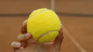 Foto van hand die gele tennisbal vasthoudt.