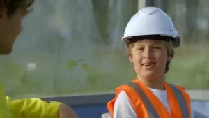 Foto van jongen met een bouwhelm op en een oranje hesje aan