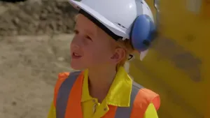 Foto van jongen met bouwhelm op en een oranje hesje aan