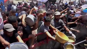 Een foto van mensen in Gaza die voedselhulp krijgen, ze houden pannen en bakken omhoog rechtsonder is een grote lepel die de bakken vult.