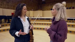 Een foto van presentatrice Janouk in gesprek met de concertmeester van het Radio Philharmonisch Orkest, een vrouw met donker haar en een viool in haar hand.
