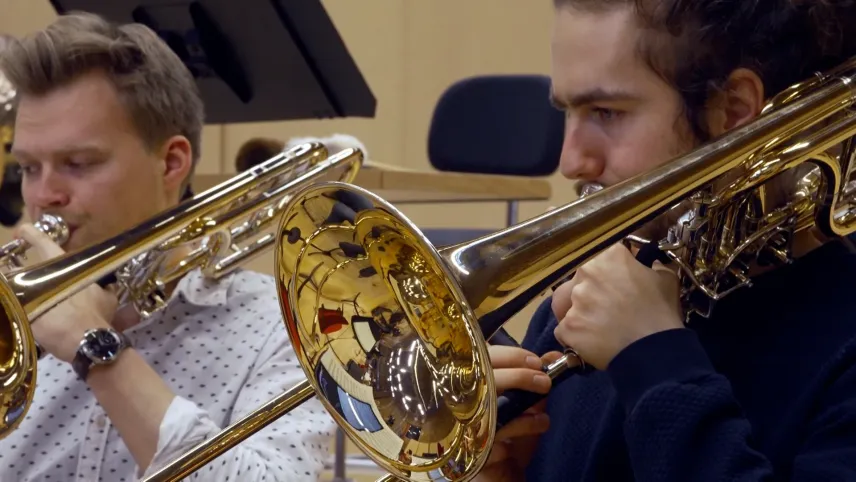 Foto van twee muzikanten die trombone spelen in het orkest.