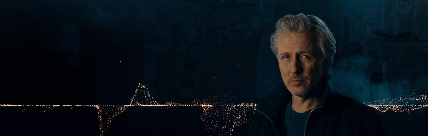 Foto van presentator Daan Schuurmans voor donkerblauwe achtergrond met goudkleurige tijdlijn.