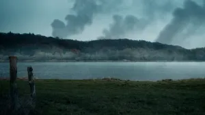 Beeld van Grebbeberg, gezien vanaf de andere kant van de rivier, met drie rookwolken die opstijgen vanuit het bos.