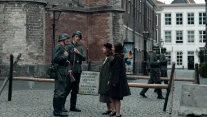 Foto van twee Duitse soldaten op Nederlandse straat tijdens de Tweede Wereldoorlog. Ze praten en lachen met twee Nederlandse meisjes.
