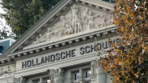 Foto van de gevel van de hollandse schouwburg in Amsterdam, een Griekse gevel met een relief en pilaren.