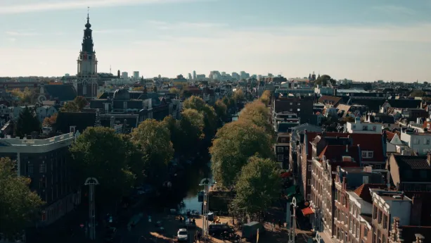 Foto van Amsterdam in de zomer, gezien vanaf bovenaf met de westertoren, grachten en grachtenpanden.