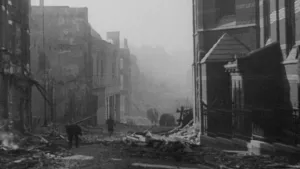 Zwartwitfoto van verwoeste Nijmeegse binnenstad na het geallieerde bombardement van 1944. Een paar mensen open tussen het puin. Er staan nog wat gevels overeind.