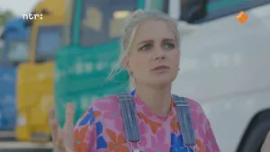 Foto van presentatrice Janouk voor een rij geparkeerde vrachtwagens.
