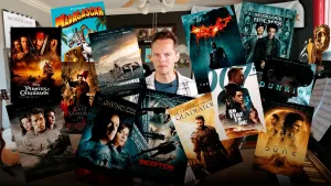 Foto van Presentator Sander Zwiep in een kamer met filmposters waar Hans Zimmer de muziek voor componeerde. We zien Pirates of The Carribean, Pearl Harbour, Madagascar, Gladiator, Inception, the dark knight, Sherlock en Dune.