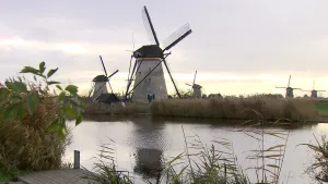 Foto van Nederlands landschap met molens bij het water, vermoedelijk Kinderdijk.