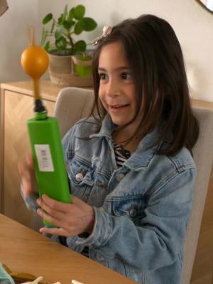 Een foto van een meisje dat aan tafel zit en een ballon opblaast met een pompje.