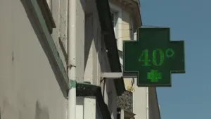 foto van een groen verlicht kruisvormig bord met de temperatuur “40°” aan de gevel van een gebouw tegen een blauwe lucht.