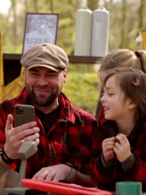 Een foto van boswachter Tim en twee kinderen in eenzelfde rood-zwart geruit overhemd.