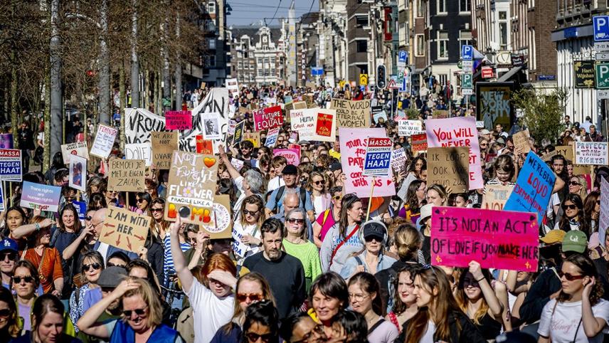 Foto van protestmars voor vrouwenrechten, mensen houden borden vast met feministische leuzen.