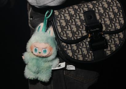 Foto van groene labubu aan een tas. 