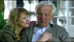 Foto van Noortje Herlaar naast een verwarde opa op een bankje, ze kijkt liefdevol naar hem.