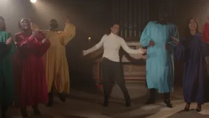 Foto van zangeres Joy tussen gospelzangers in kleurrijke gewaden.