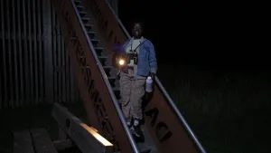 Een foto van presentatrice Tirsa in het donker. Ze staat op een trap en heeft een zaklamp, een verrekijker en een thermoskan bij zich.