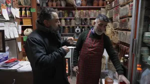 Een foto van twee mannen in een Turkse winkel. De winkel staat vol potten met ingemaakt voedsel en rieten manden.