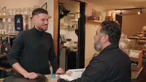 Een foto van twee mannen in een ijssalon / koffiezaak. De man achter de balie is van Italiaanse afkomst, de man die iets bestelt is van Turkse afkomst.