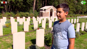 Een jongen staat op een begraafplaats bij de oorlogsgraven