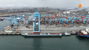 Luchtfoto van haven met honderden gekleurde containers en blauwe hijskraan.