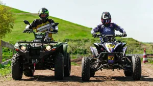 Foto van twee quads op een zandweg, bestuurders zijn ingepakt in beschermende pakken en met helm.