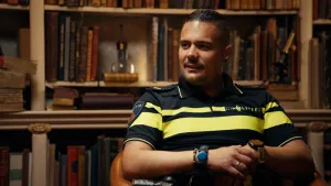 Foto van politieagent in uniform voor een oude boekenkast.