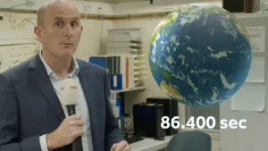 Foto van presentator met aardbol waaronder het getal 86.400 seconden staat.