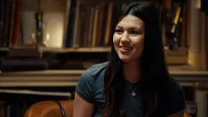 Foto van tienermoeder Megan voor een oude boekenkast.
